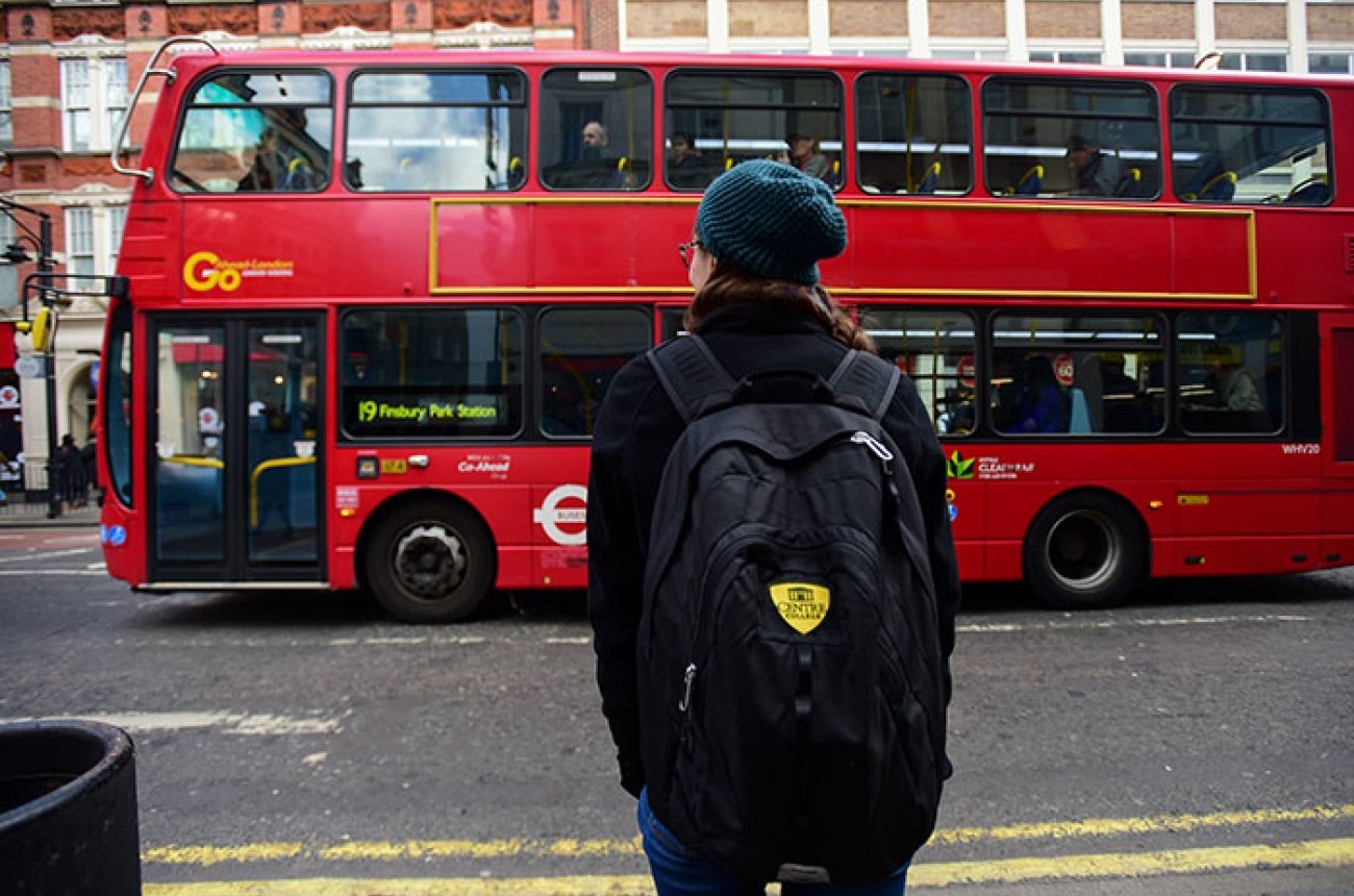 Centre student facing a red double-decker bus in London