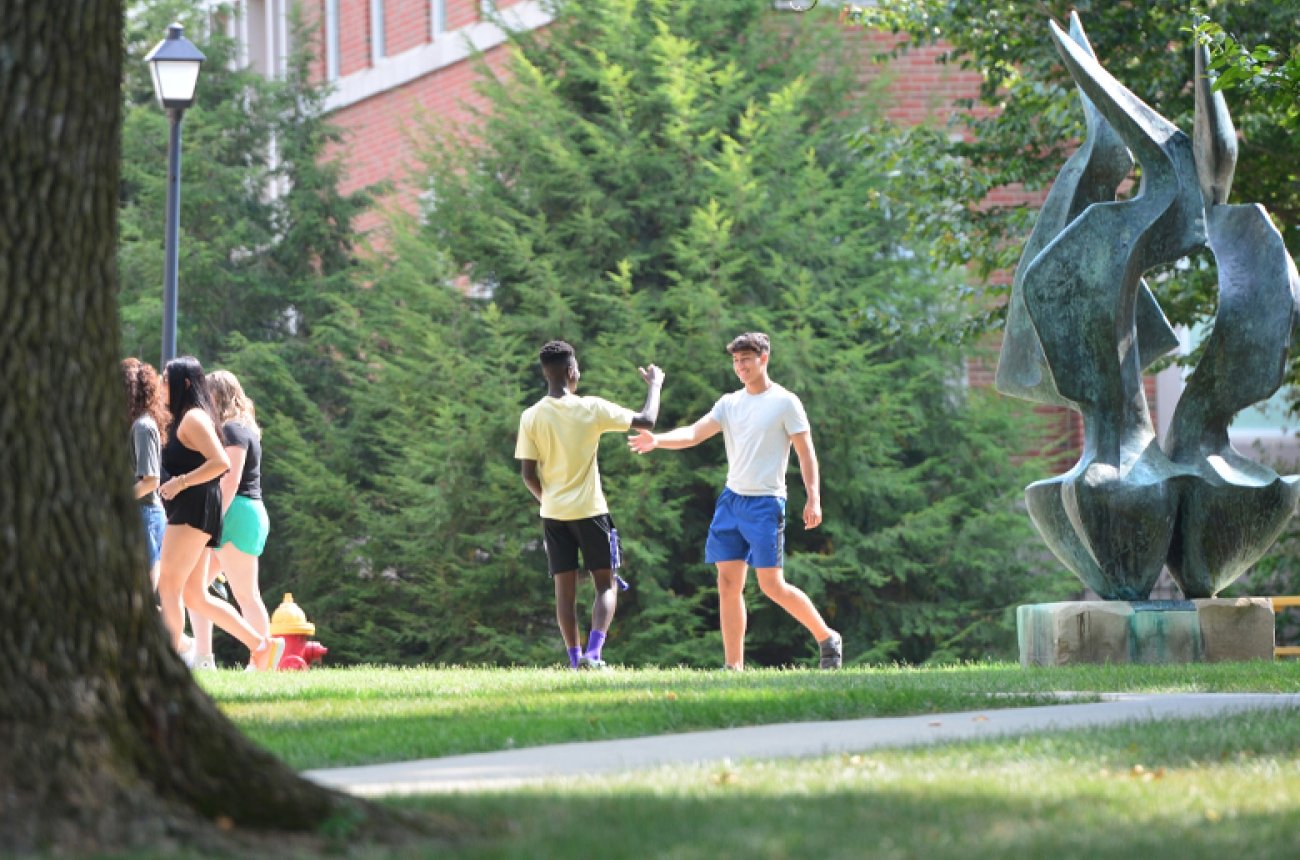 Students high-fiving walking on campus
