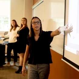 Female student presenting information from a projected image
