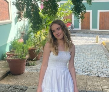 Student wearing sun dress and smiling at camera