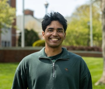 Student wearing half zip pullover and smiling at photographer