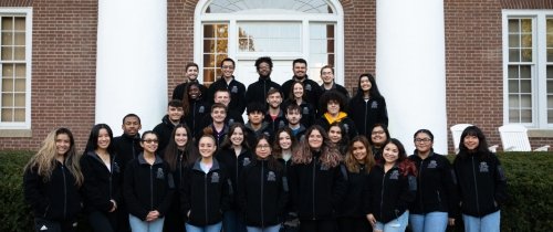 Large group of students standing in front of Old Centre with matching fleece jackets with Grissom student logo