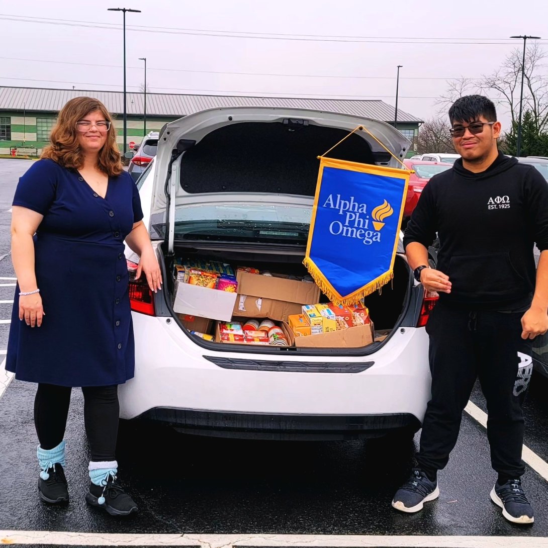 Students standing at car with open trunk showing collected food from APO food drive to benefit the New Hope Food Pantry
