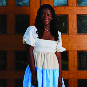 Student wearing multicolored dress and smiling at camera