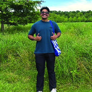 Student standing in field wearing blue top and dark jeans