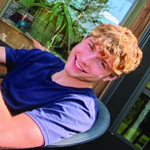Student sitting in a patio chair and smiling at camera