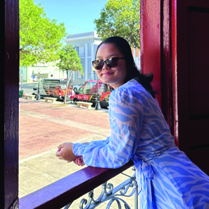 student leaning on railing, looking over left shoulder and smiling at camera