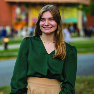 Student standing in front of Norton Center and smiling at camera