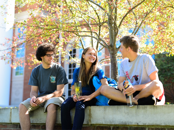Three students sitting on bench at the library