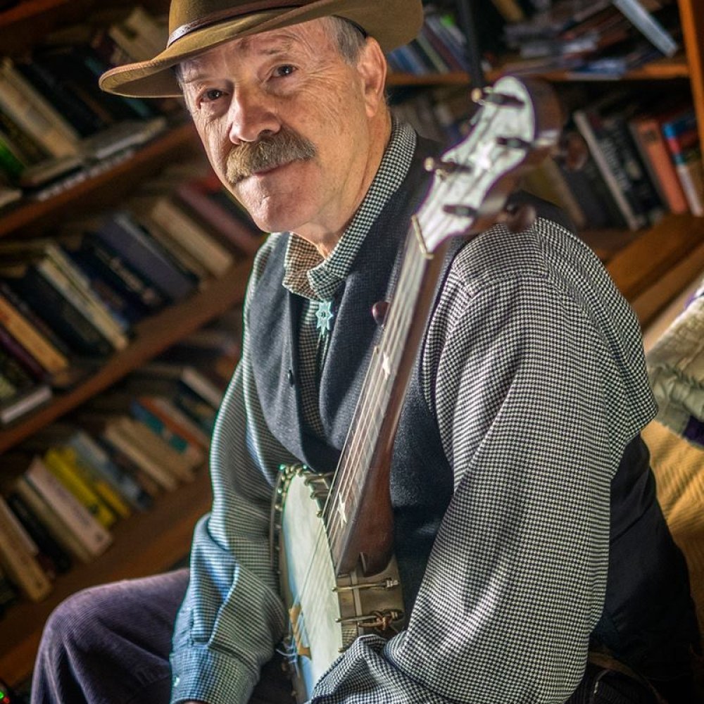 Person wearing brown hat while holding a banjo