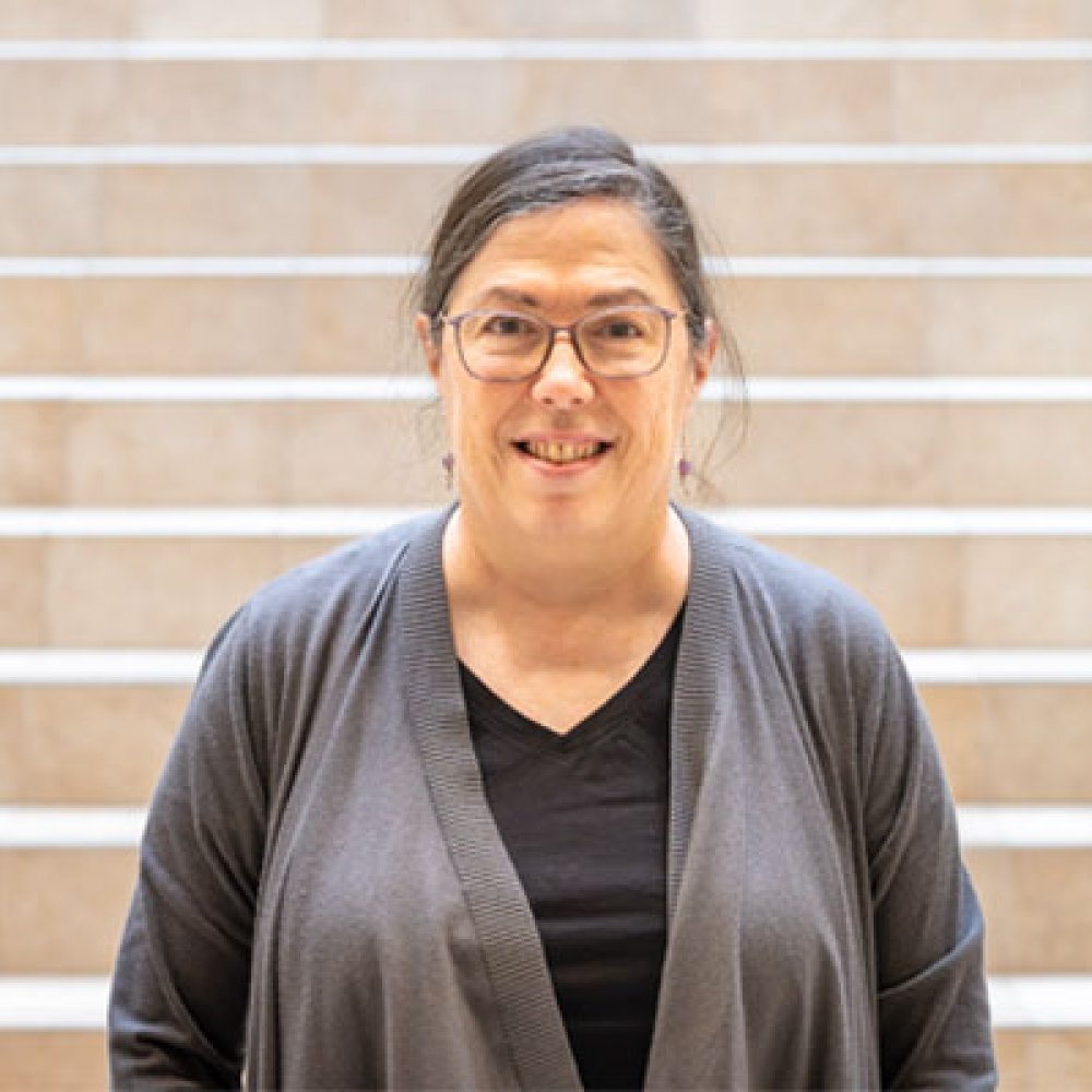 Person wearing glasses smiling standing in front of staircase