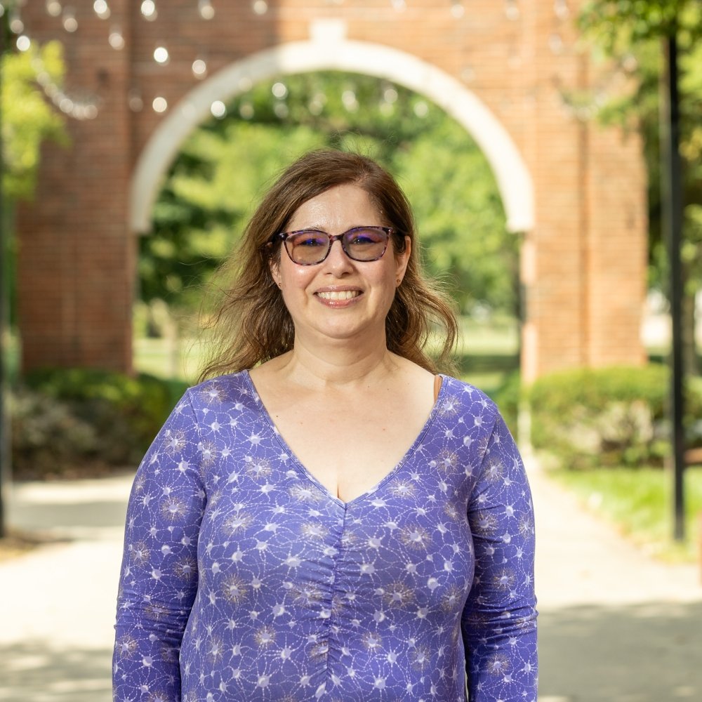 Lady with purple top standing outside on campus