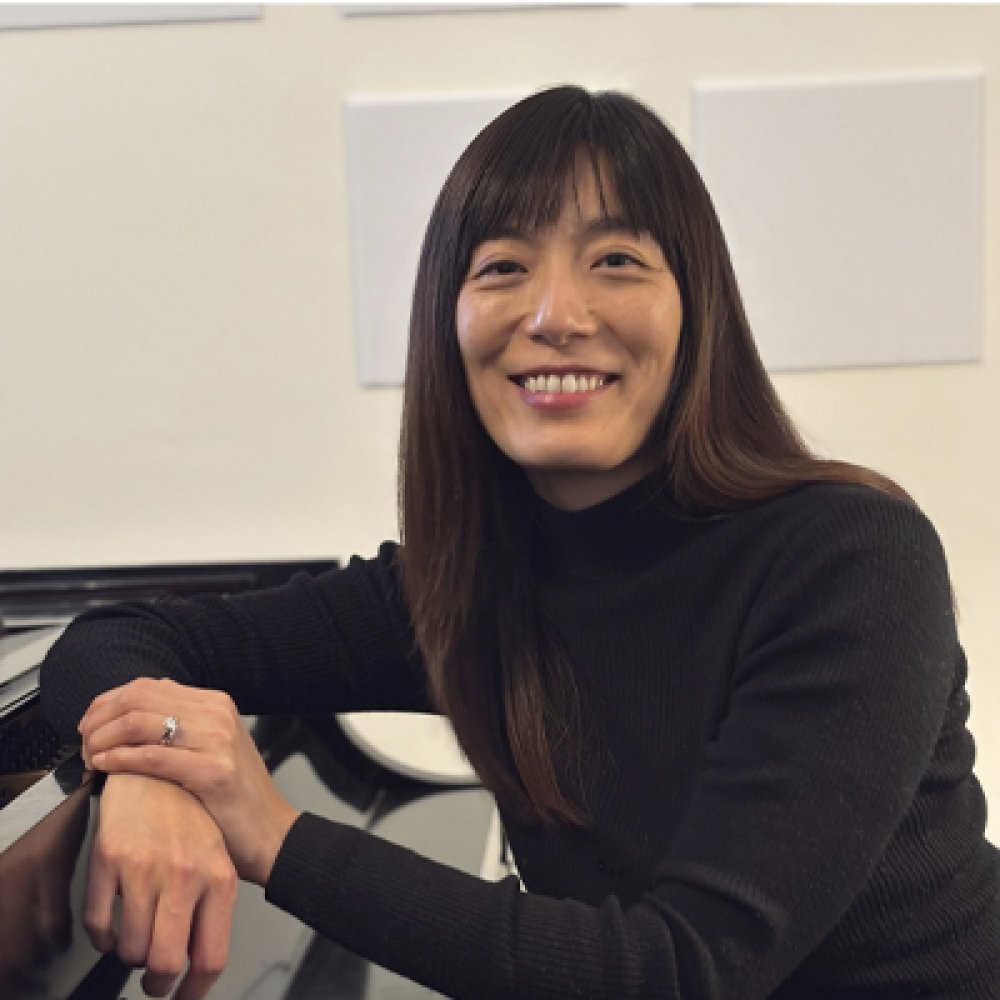 Person smiling while seated next to piano