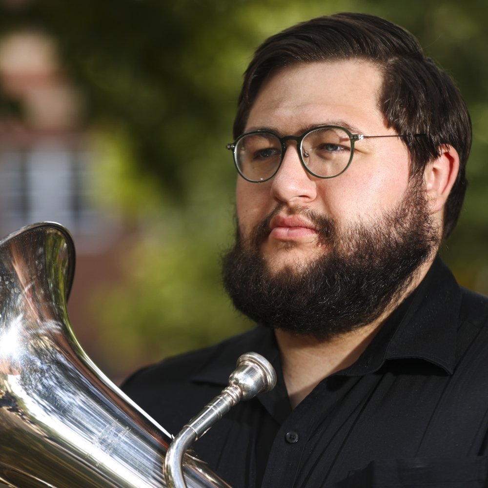 Man wearing glasses holding a euphonium music instrument