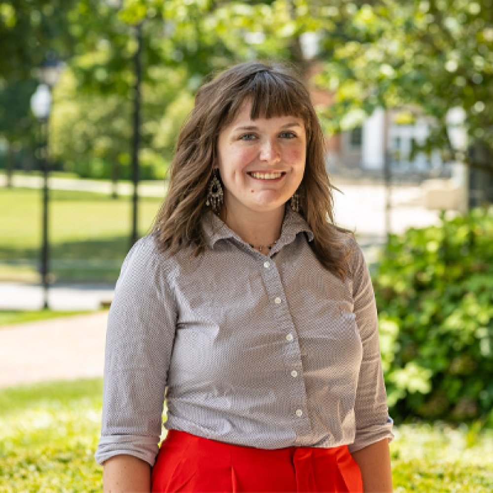 Person wearing button up shirt and red pants and smiling at camera