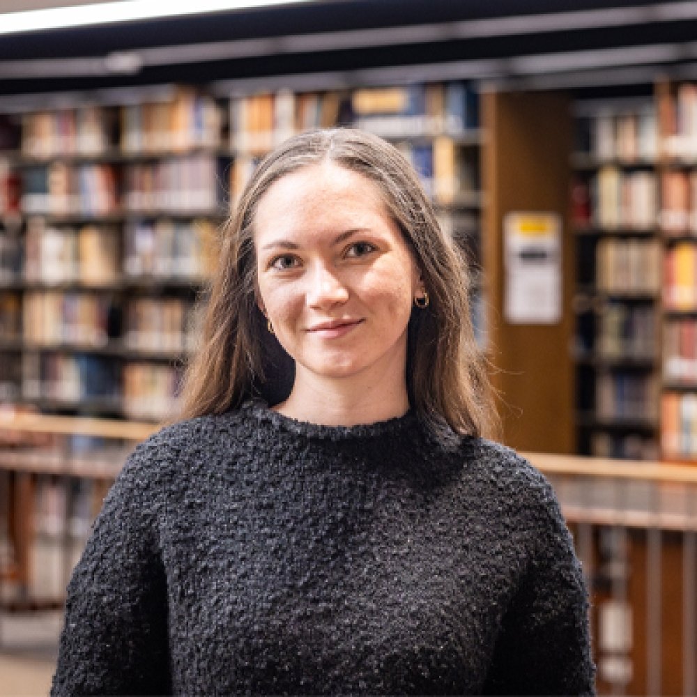 Person standing inside library and smiling at photographer