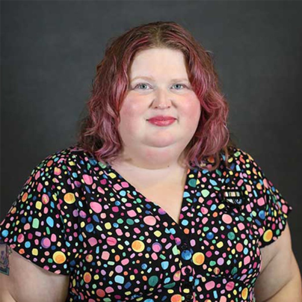 Person wearing colorful top and smiling at photographer