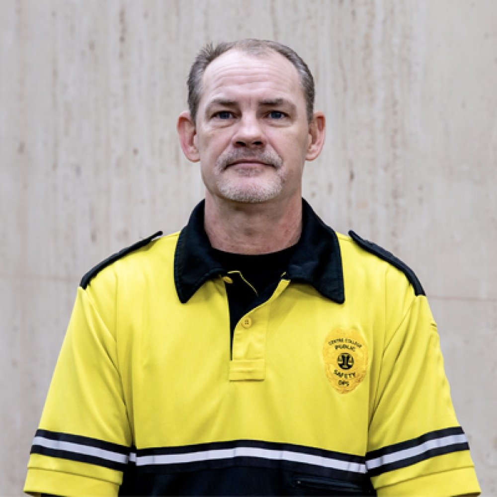 Person wearing gold and black polo top with DPS badge logo
