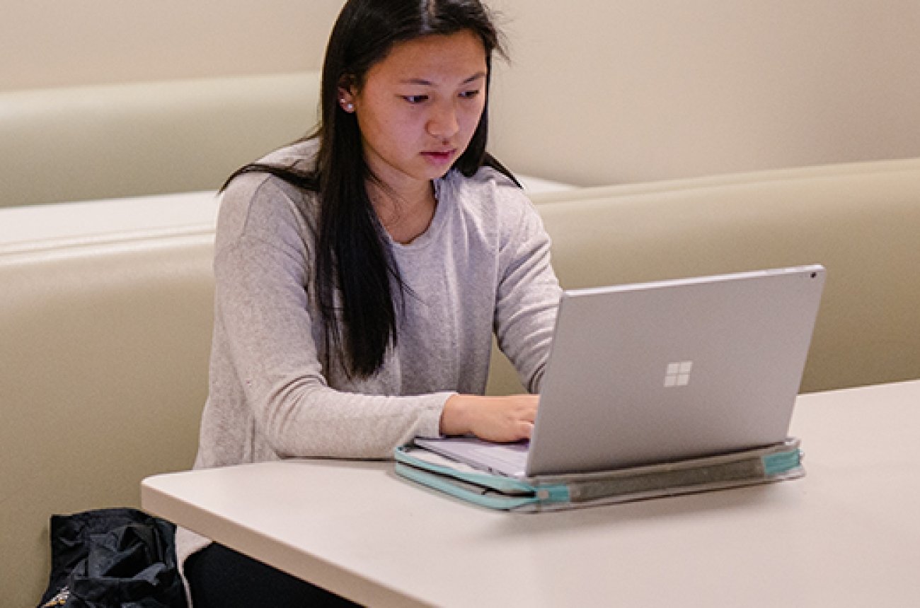 Student working on laptop computer in a booth at the library