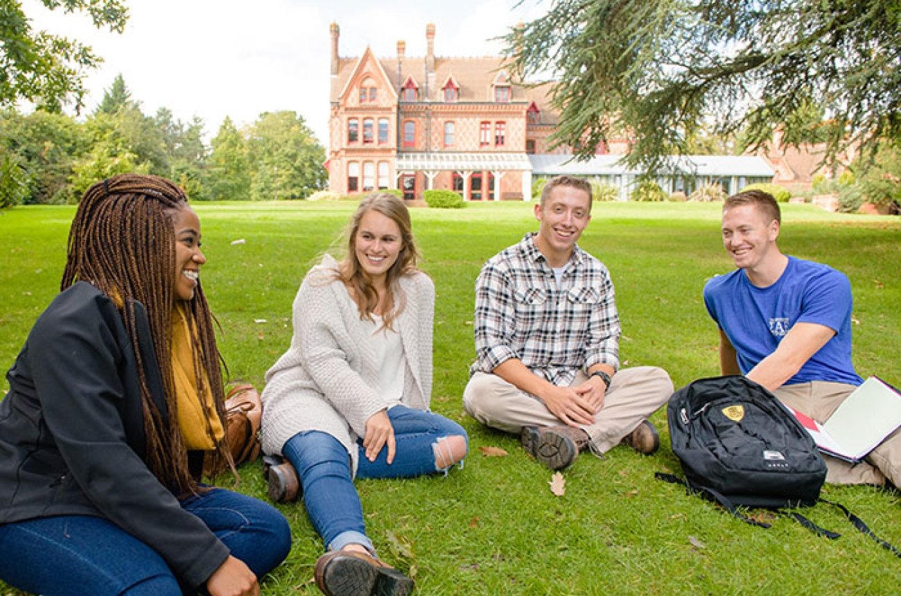 Centre students laughing on a grassy lawn
