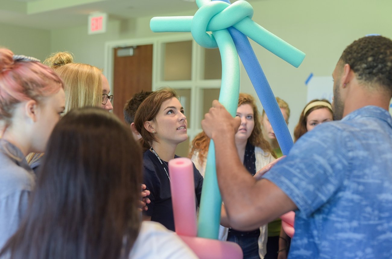 Group of students doing a team building activity with pool noodles