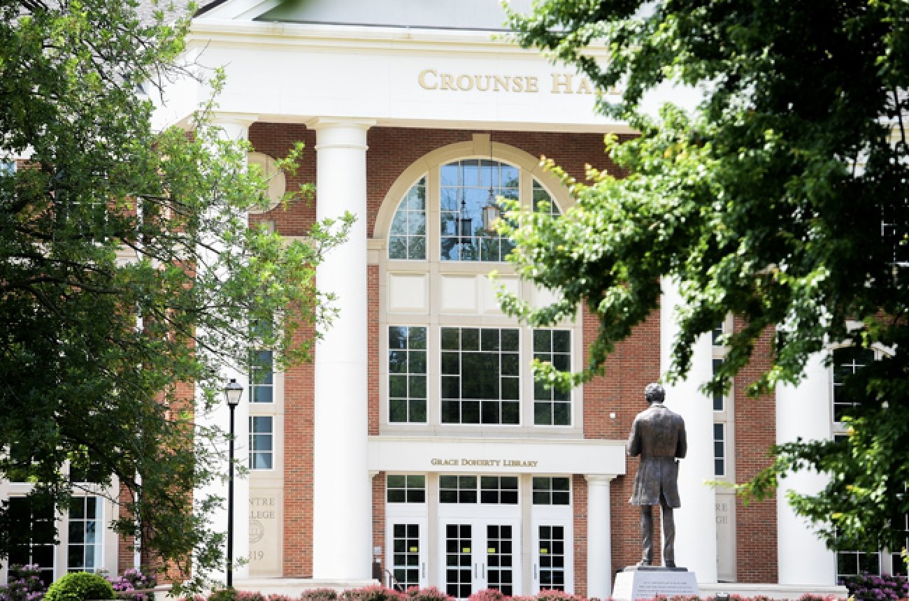 outside view of library multi floor building with glass doors and statue of abraham lincoln green trees framing the outside edges of the photo