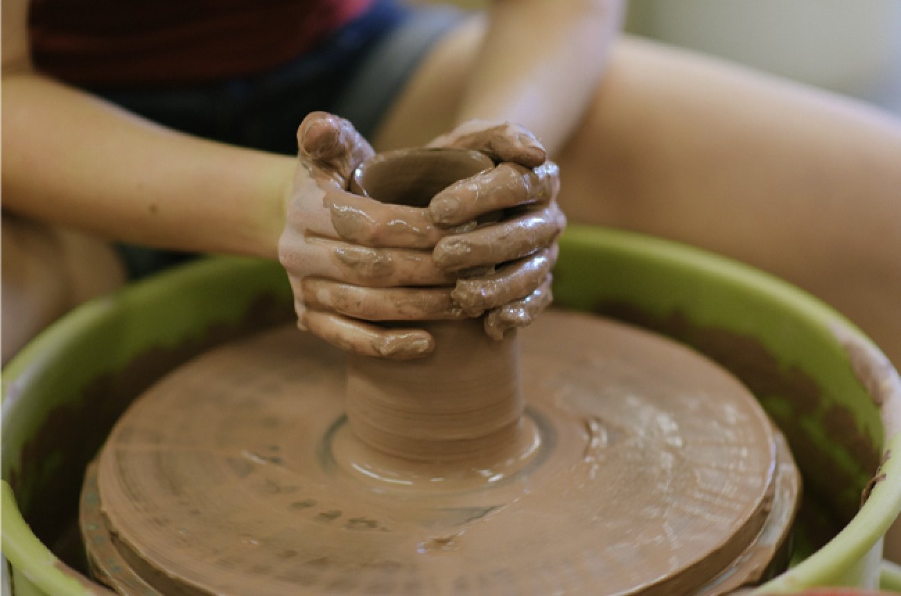student using clay wheel in ceramics class