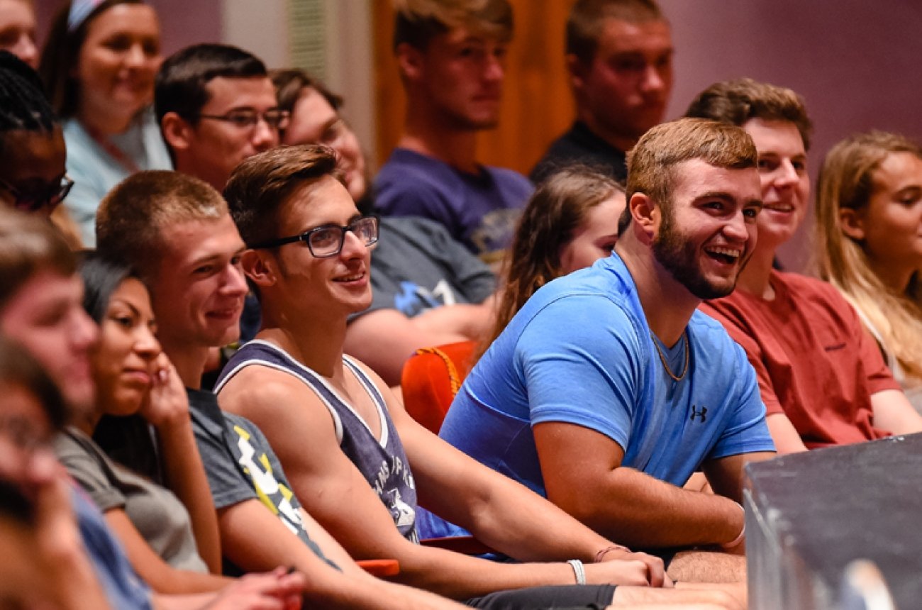 College students listening to speaker inside auditorium