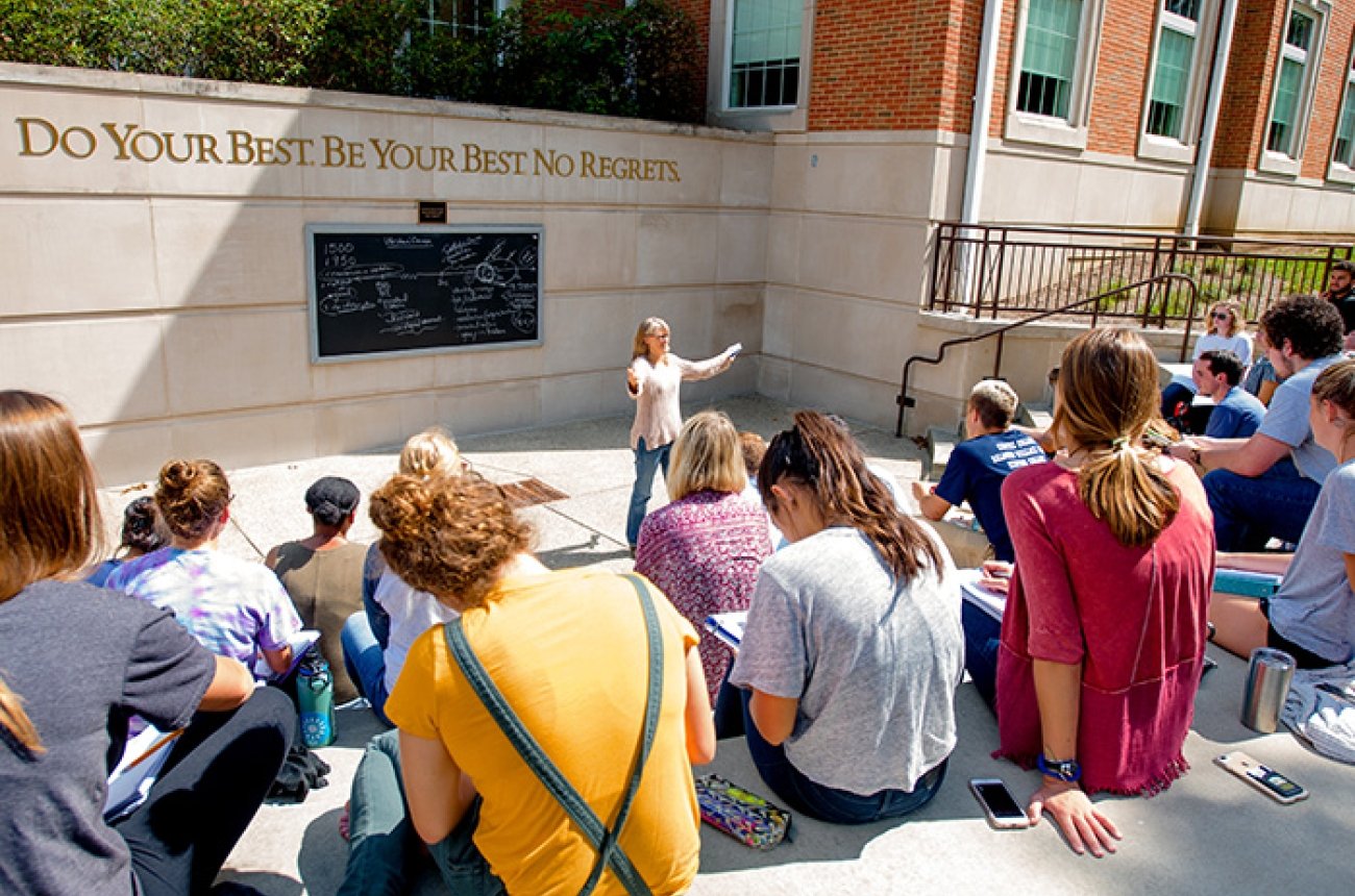 Professor teaching outside in small outdoor amphitheater classroom while students watch