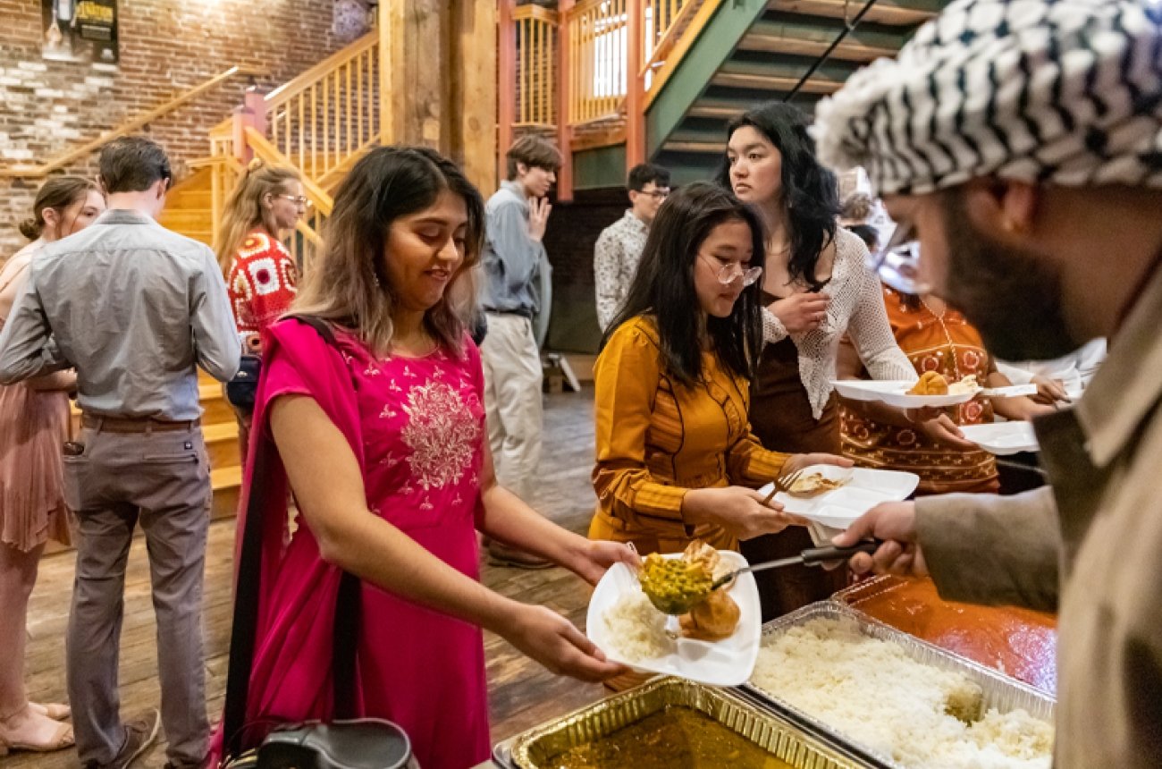 Students walking through buffet line for food at multicultural ball
