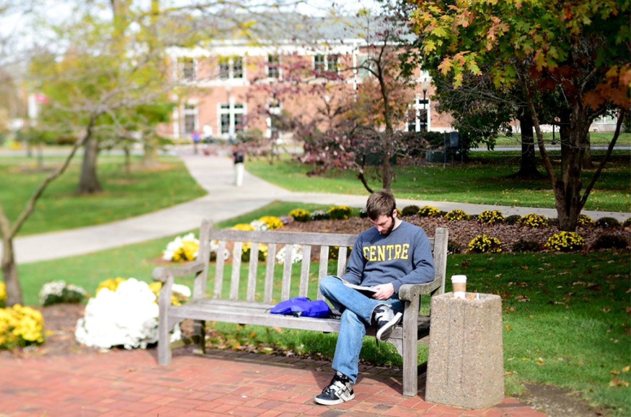 Student reading on a bench in the spring