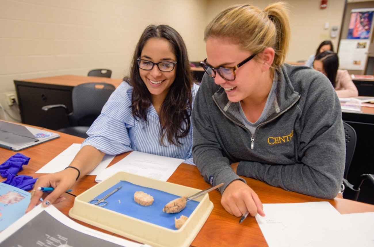 Two female students participating in a lab dissecting