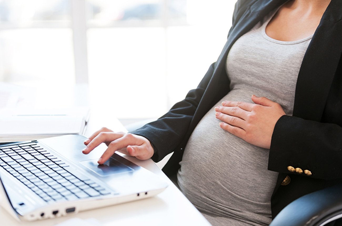 Pregnant woman sitting and working on a computer