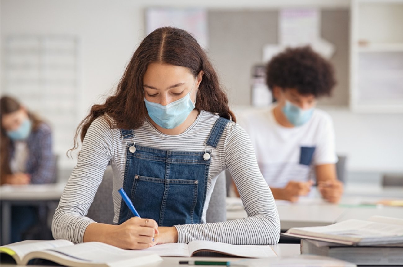 Shutterstock image of student wearing mask and students in class behind her wearing masks