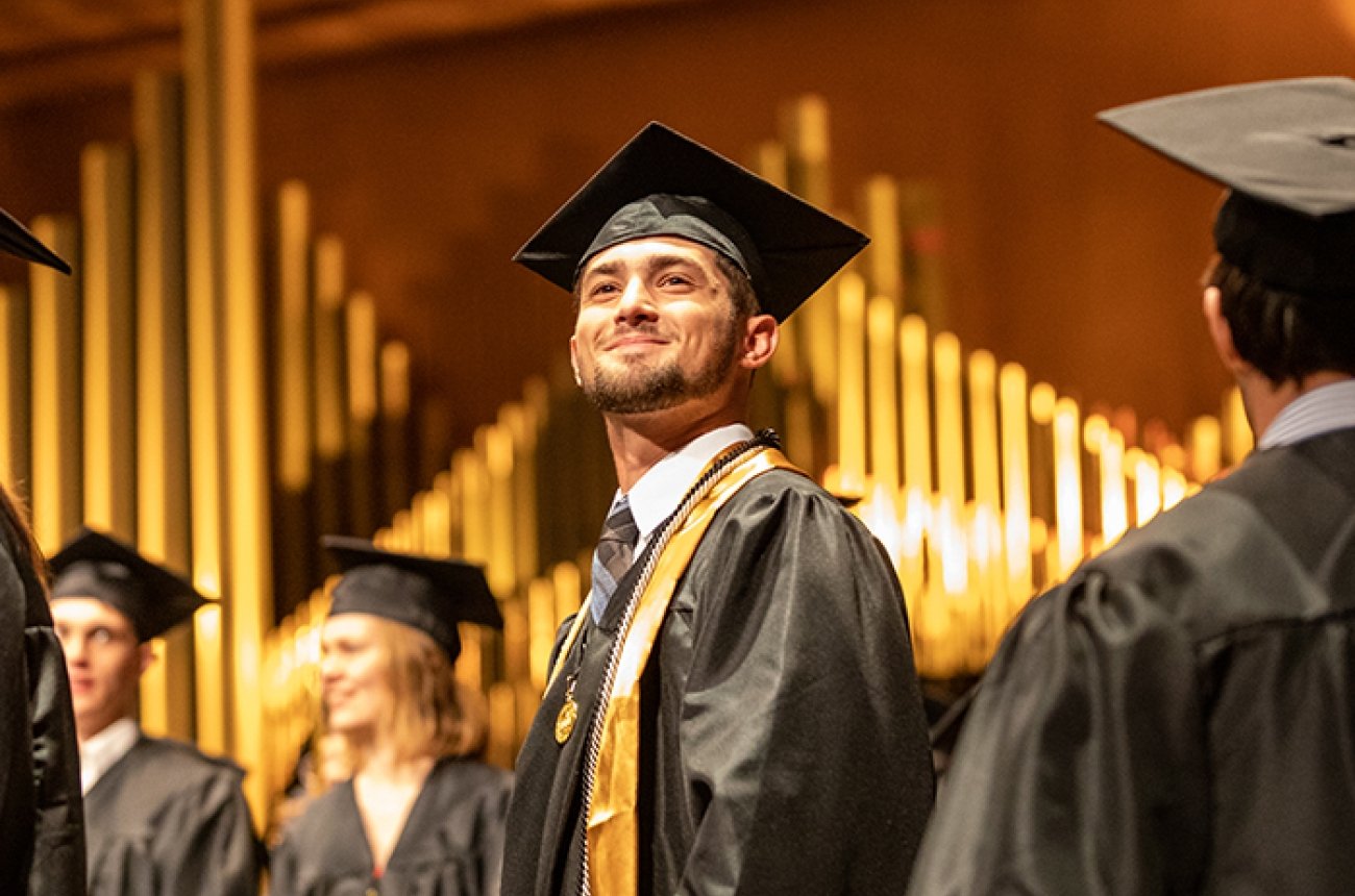 student looking at audience in cap and gown at graduation ceremony