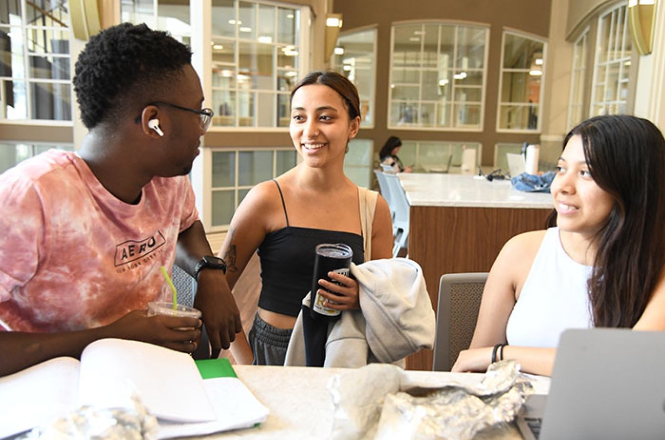 Three students talking at a table
