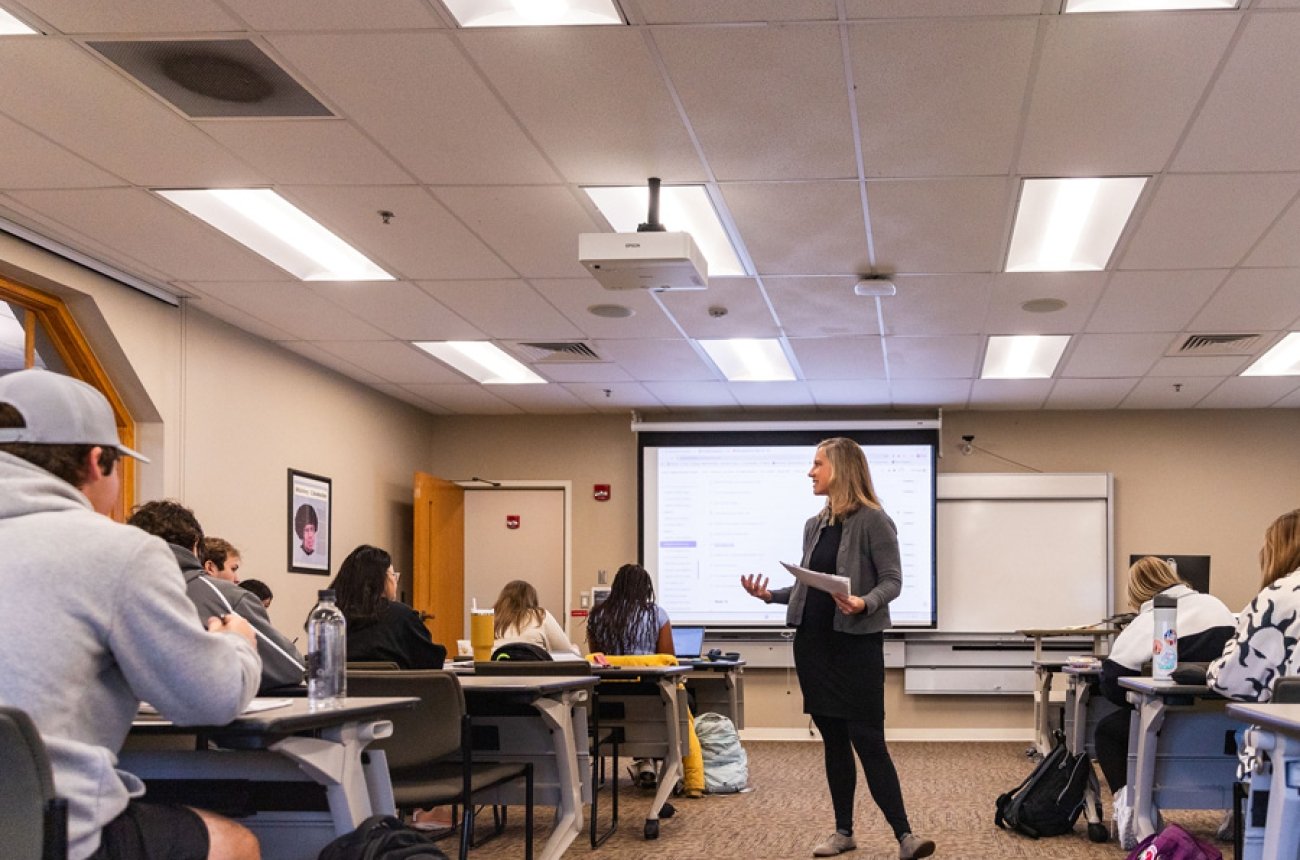 Professor teaching class while students listen sitting at desks