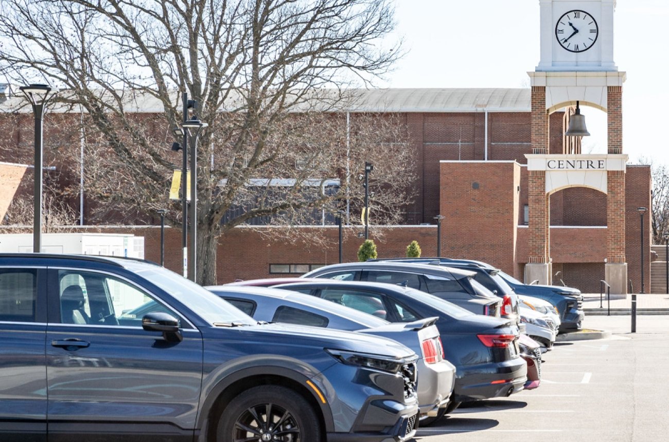 cars parked in lot near bell tower on campus