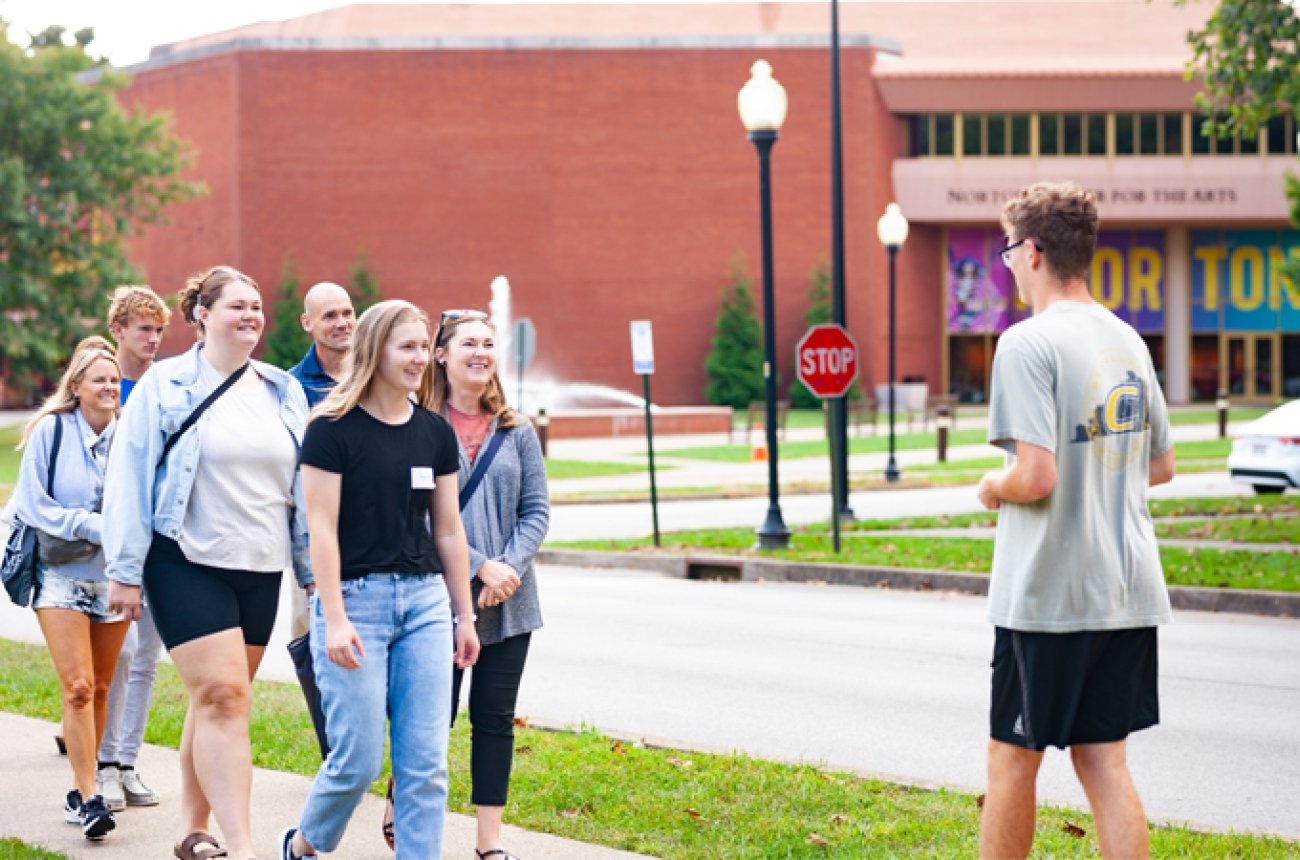 Student giving campus tour to large group walking in front of Norton Center