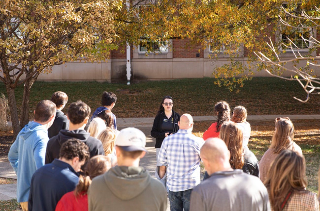 students and parents in a large group listening to a student tour guide