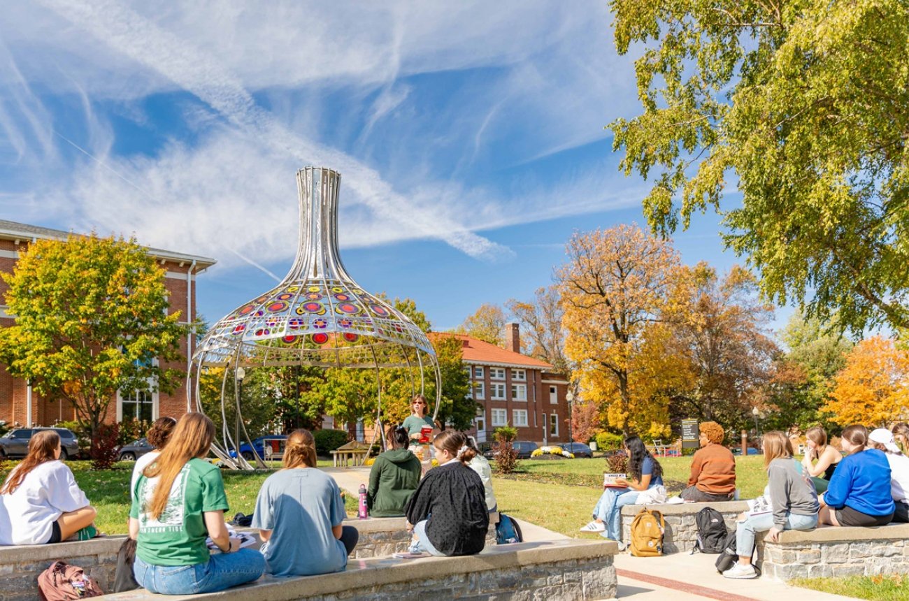 Outdoor Classroom students sitting in front of the Stephen Powell memorial