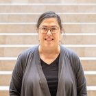 Person wearing glasses smiling standing in front of staircase