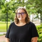 Person wearing black top and glasses and smiling at camera
