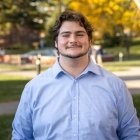 Student wearing button up shirt and smiling at camera