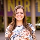 Person wearing multi colored top and smiling at camera