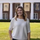 Person wearing white top with dark pants and smiling at camera