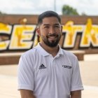 Person wearing white Centre logo Polo short sleeve and smiling at camera