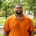Person wearing an orange polo shirt and smiling at camera