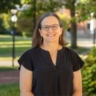 Person wearing glasses and black top smiling at photographer