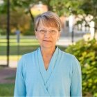 Person wearing light blue blouse and glasses smiling at photographer